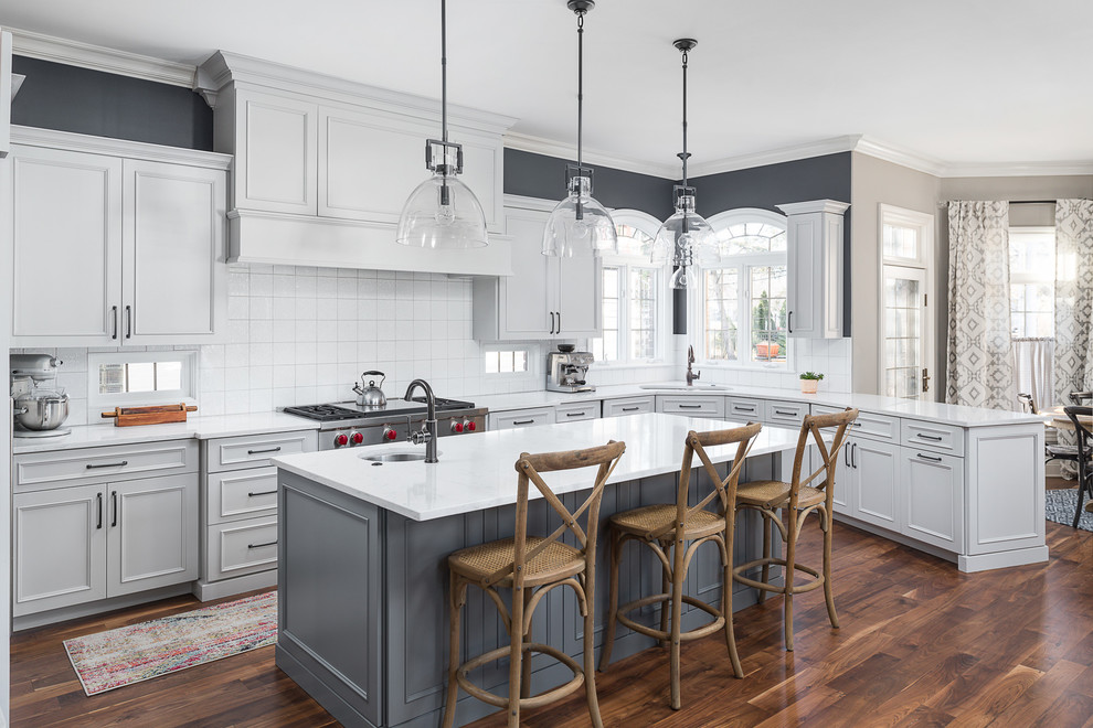 Large transitional l-shaped medium tone wood floor and brown floor eat-in kitchen photo in Chicago with an undermount sink, white cabinets, quartz countertops, white backsplash, ceramic backsplash, stainless steel appliances, an island, white countertops and recessed-panel cabinets