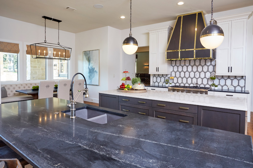 This is an example of a mid-sized eclectic l-shaped eat-in kitchen in Dallas with a double-bowl sink, shaker cabinets, white cabinets, marble benchtops, white splashback, porcelain splashback, stainless steel appliances, medium hardwood floors and multiple islands.
