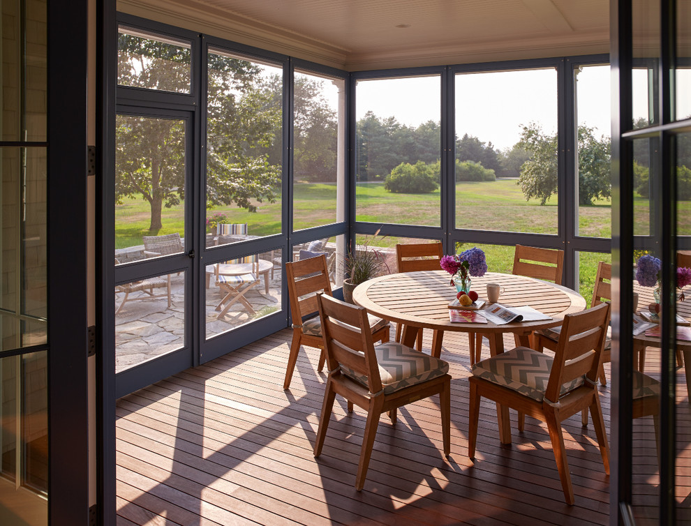 This is an example of a large traditional medium tone wood floor porch design in Portland Maine with a standard ceiling and no fireplace.