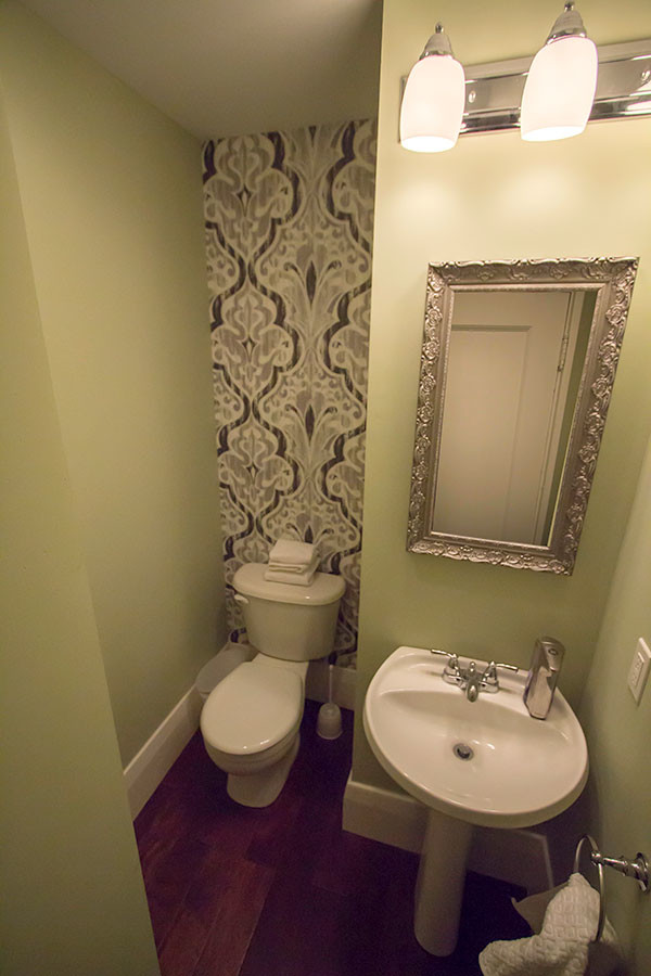 Small contemporary 3/4 bathroom in Toronto with a two-piece toilet, green walls, dark hardwood floors, a pedestal sink and solid surface benchtops.
