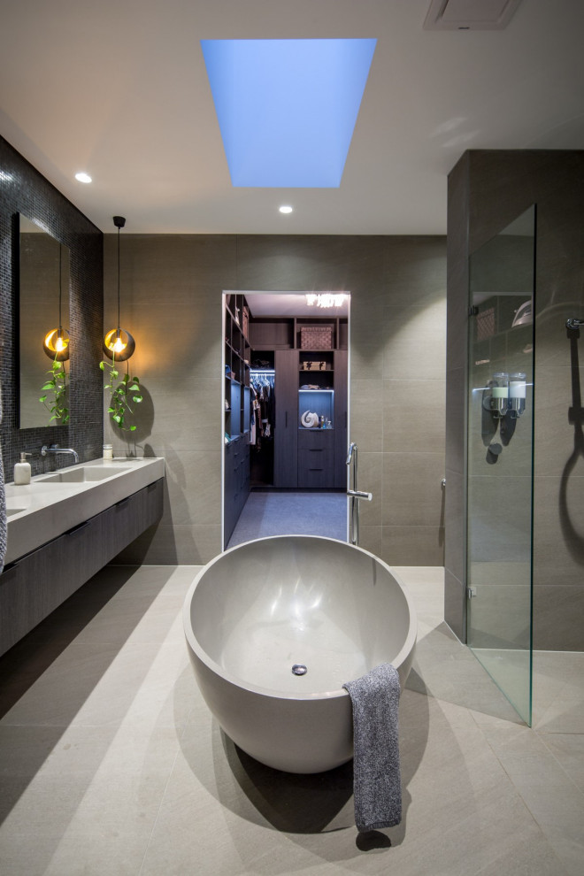 This is an example of a contemporary bathroom in Melbourne with dark wood cabinets, a freestanding tub, an integrated sink, grey floor, an open shower, grey benchtops, a double vanity and a floating vanity.