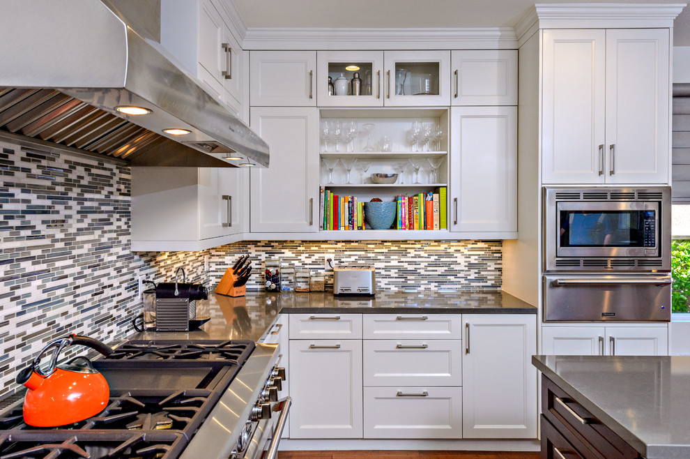 Transitional u-shaped kitchen photo in San Diego with a farmhouse sink, recessed-panel cabinets, white cabinets, quartz countertops, multicolored backsplash, matchstick tile backsplash and stainless steel appliances