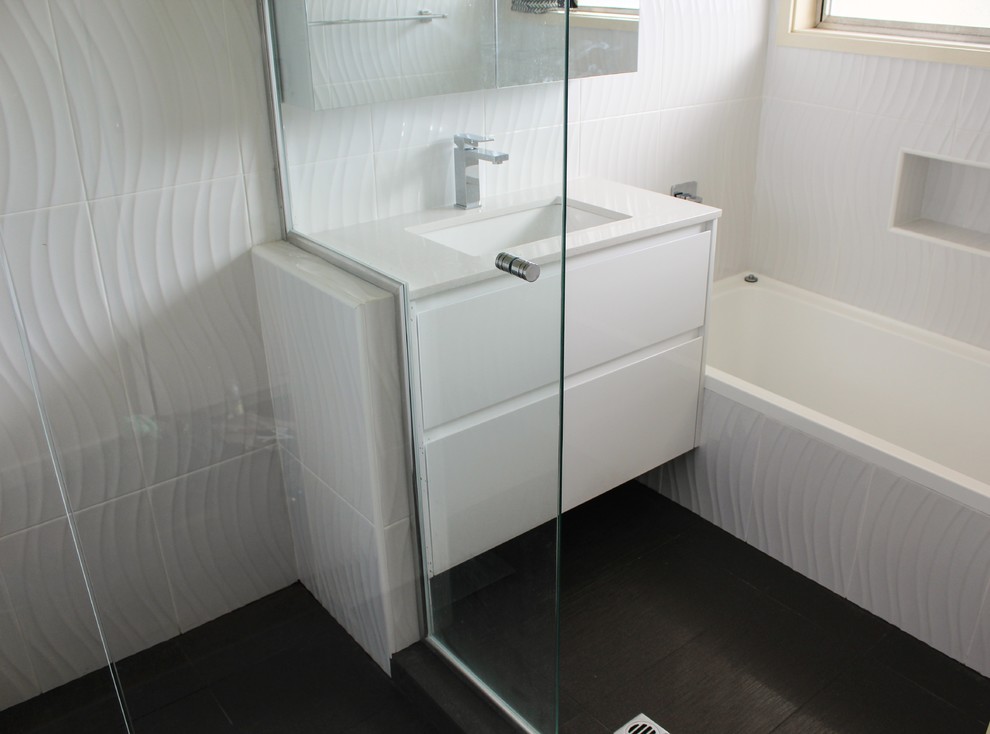 Inspiration for a small modern 3/4 bathroom in Perth with open cabinets, white cabinets, a drop-in tub, a corner shower, gray tile, porcelain tile, white walls, porcelain floors, an undermount sink and engineered quartz benchtops.