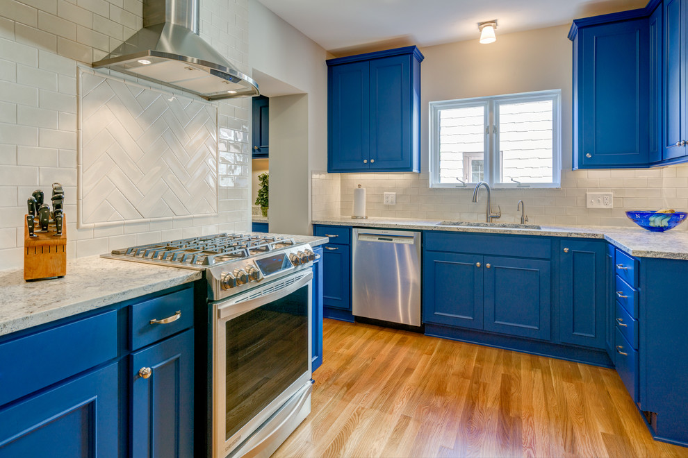 Example of a transitional light wood floor kitchen design in Columbus with an undermount sink, recessed-panel cabinets, blue cabinets, marble countertops, white backsplash and stainless steel appliances