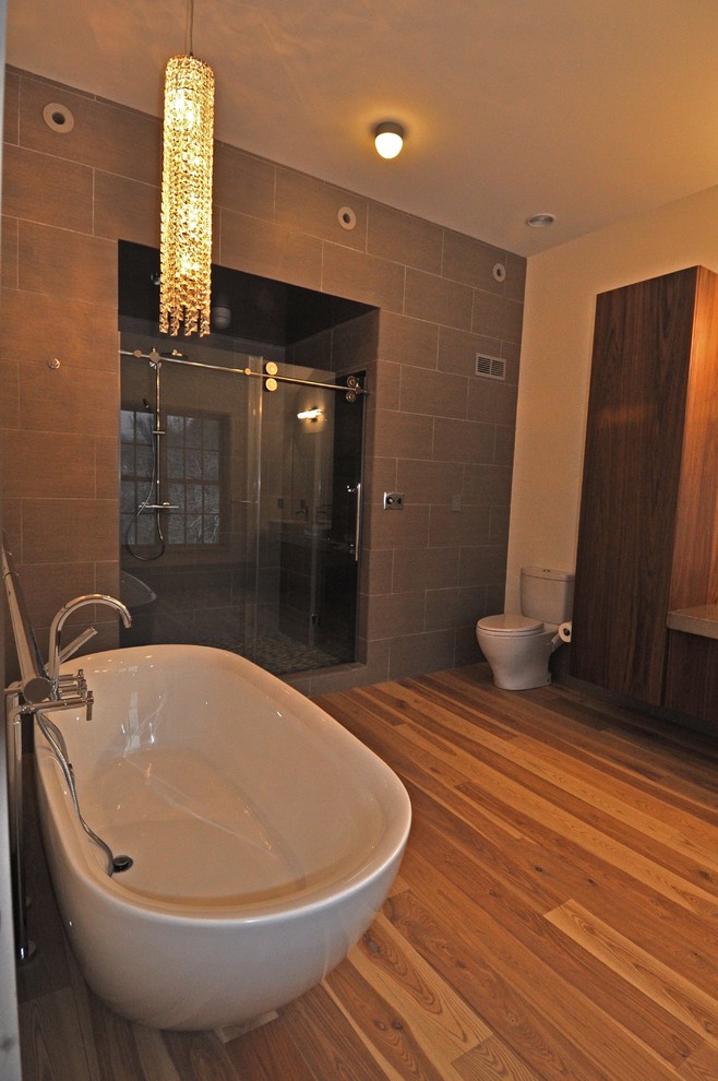 Freestanding bathtub - large transitional master gray tile and ceramic tile medium tone wood floor and beige floor freestanding bathtub idea in Boston with flat-panel cabinets, dark wood cabinets, a two-piece toilet, beige walls and a vessel sink