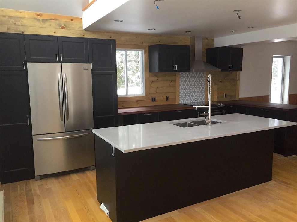 Inspiration for a mid-sized contemporary l-shaped kitchen in Montreal with a double-bowl sink, recessed-panel cabinets, black cabinets, wood benchtops, timber splashback, stainless steel appliances, medium hardwood floors and with island.