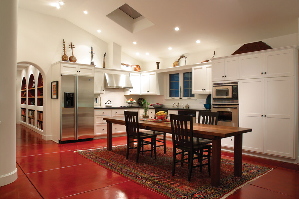 Photo of a mediterranean l-shaped kitchen in Los Angeles with stainless steel appliances, shaker cabinets, white cabinets and red floor.