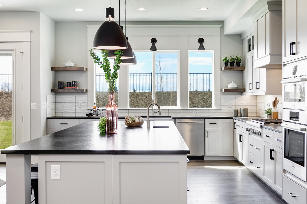 Inspiration for a large transitional l-shaped kitchen in Boise with an undermount sink, shaker cabinets, turquoise cabinets, white splashback, with island, brown floor and black benchtop.