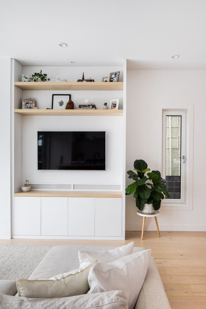 Kleines Skandinavisches Wohnzimmer im Loft-Stil mit weißer Wandfarbe, Gaskamin, Kaminumrandung aus Beton, TV-Wand, beigem Boden und hellem Holzboden in Vancouver