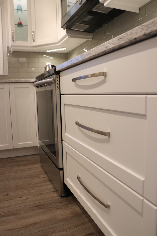 Inspiration for a small transitional u-shaped eat-in kitchen remodel in Edmonton with an undermount sink, recessed-panel cabinets, white cabinets, quartz countertops, gray backsplash, glass tile backsplash, stainless steel appliances, no island and white countertops