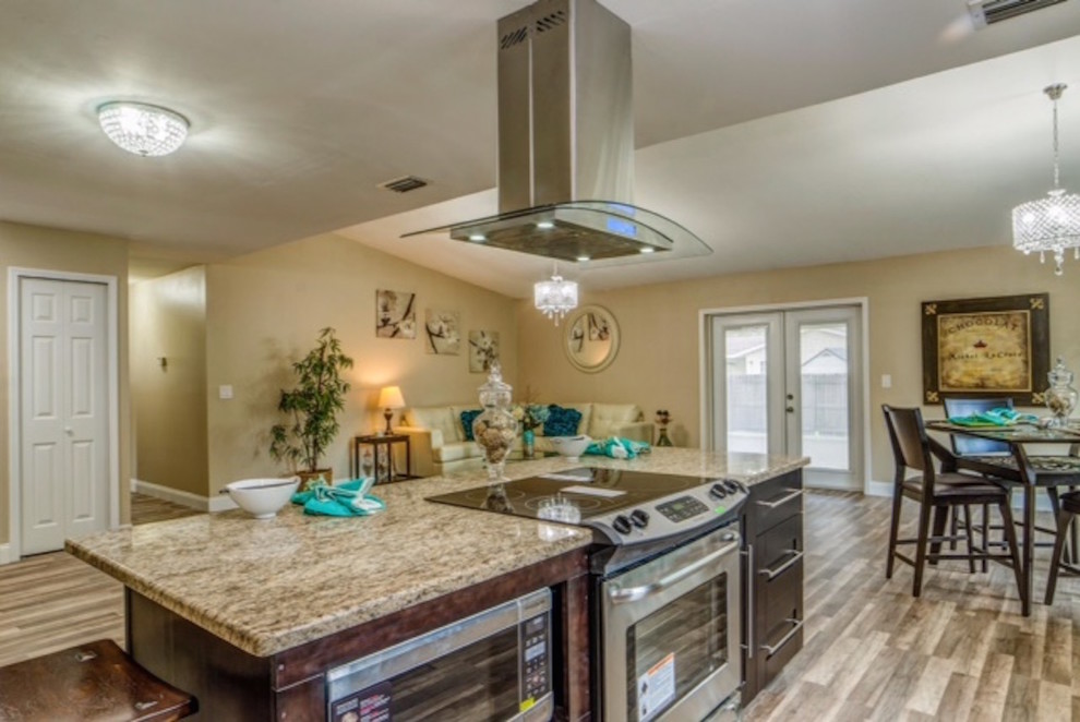 Mid-sized modern galley eat-in kitchen in Tampa with dark wood cabinets, granite benchtops, beige splashback, stainless steel appliances, with island, shaker cabinets, stone tile splashback and a single-bowl sink.