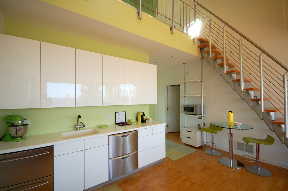 This is an example of a small contemporary single-wall eat-in kitchen in Minneapolis with an integrated sink, flat-panel cabinets, white cabinets, stainless steel appliances, laminate benchtops and cork floors.