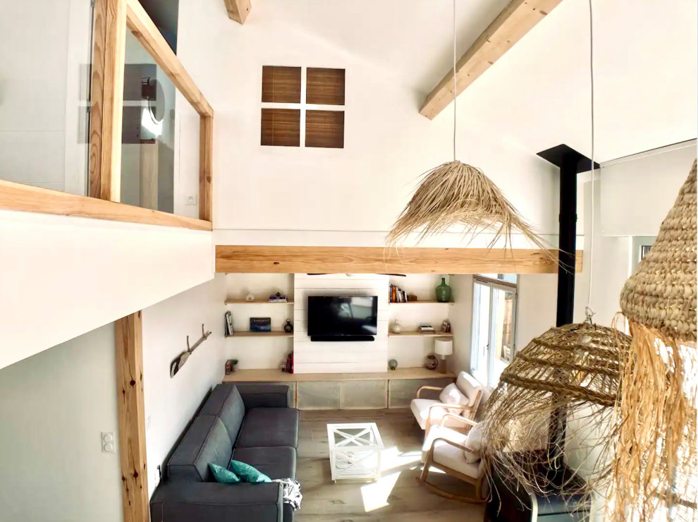 Идея дизайна: открытая гостиная комната в белых тонах с отделкой деревом в морском стиле с с книжными шкафами и полками и телевизором на стене