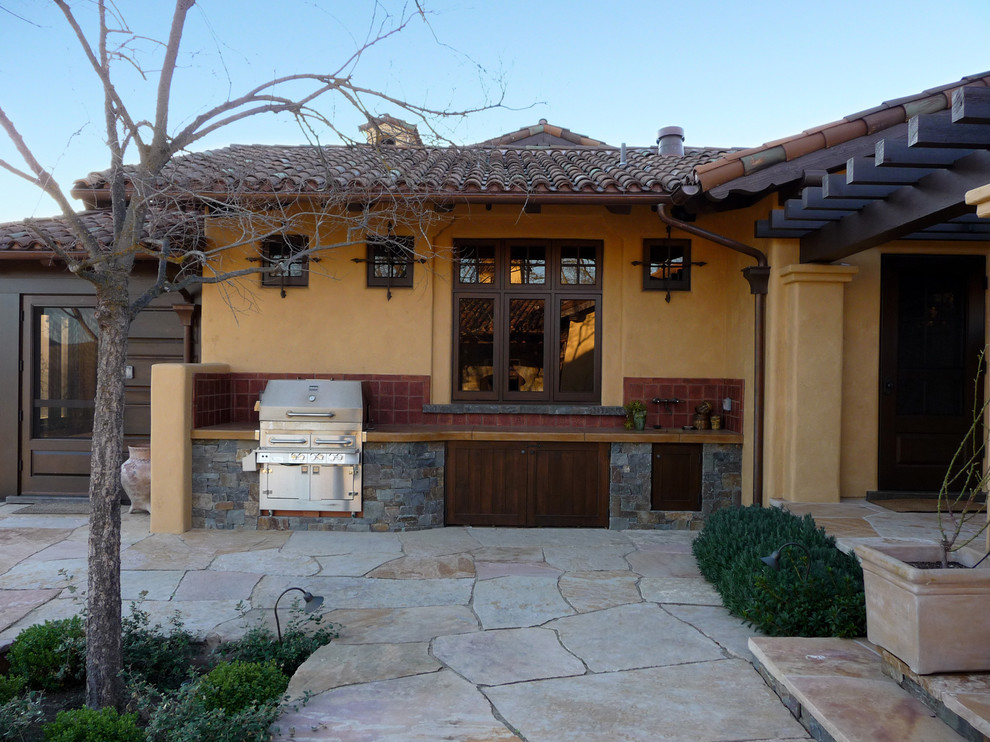 Mediterranean backyard patio in San Francisco with an outdoor kitchen, natural stone pavers and a roof extension.