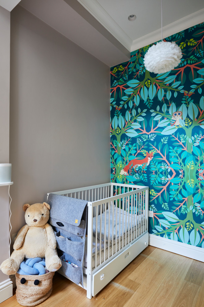 This is an example of a small modern gender-neutral nursery in London with beige walls, light hardwood floors, brown floor and coffered.