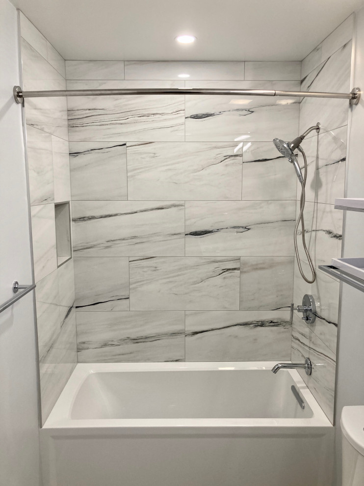 Photo of a medium sized modern ensuite bathroom in DC Metro with flat-panel cabinets, grey cabinets, an alcove bath, an alcove shower, a two-piece toilet, white tiles, porcelain tiles, grey walls, porcelain flooring, a submerged sink, quartz worktops, grey floors, a shower curtain, white worktops, a single sink and a floating vanity unit.