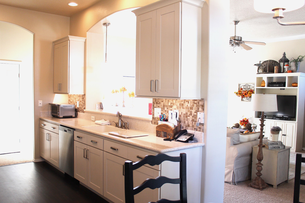 Eat-in kitchen - transitional galley eat-in kitchen idea in Boise with an integrated sink, shaker cabinets, white cabinets, solid surface countertops, beige backsplash, glass tile backsplash and stainless steel appliances
