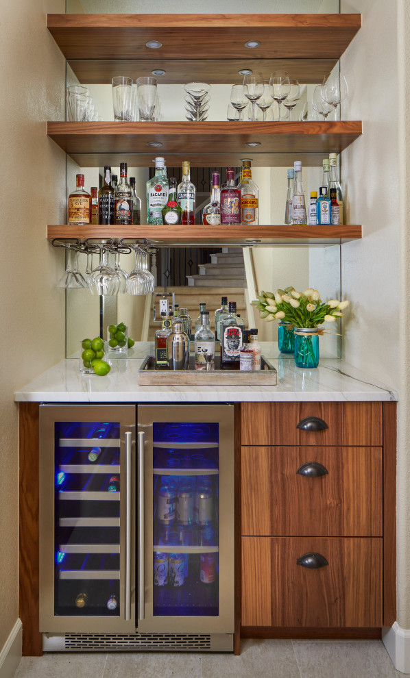 This is an example of a mid-sized contemporary u-shaped home bar in Denver with flat-panel cabinets, medium wood cabinets, quartzite benchtops, porcelain floors, white benchtop, mirror splashback and grey floor.