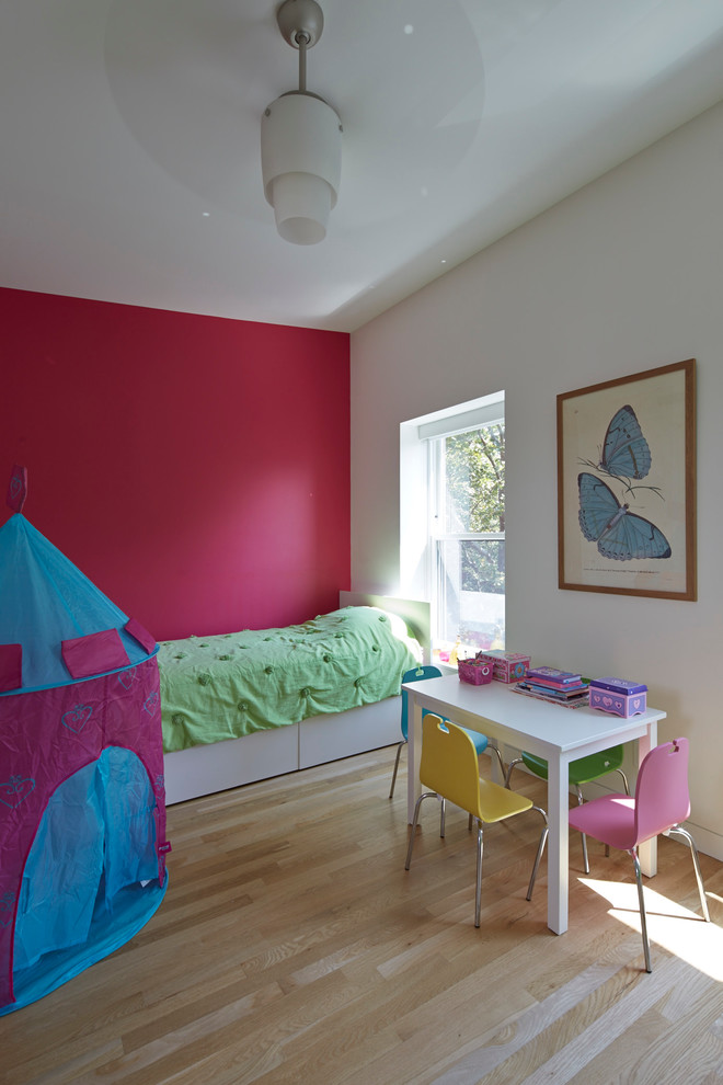 Design ideas for a mid-sized contemporary kids' bedroom for kids 4-10 years old and girls in New York with pink walls and light hardwood floors.