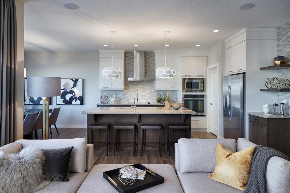 Design ideas for a mid-sized transitional galley eat-in kitchen in Calgary with an undermount sink, flat-panel cabinets, beige cabinets, quartz benchtops, grey splashback, ceramic splashback, stainless steel appliances, medium hardwood floors and with island.