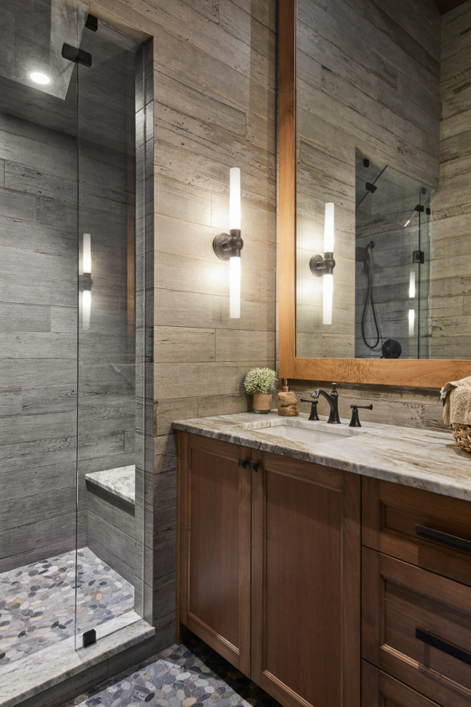 This is an example of a large country bathroom in Other with shaker cabinets, medium wood cabinets, an alcove shower, gray tile, wood-look tile, grey walls, pebble tile floors, an undermount sink, granite benchtops, grey floor, a hinged shower door, a single vanity, a built-in vanity and beige benchtops.