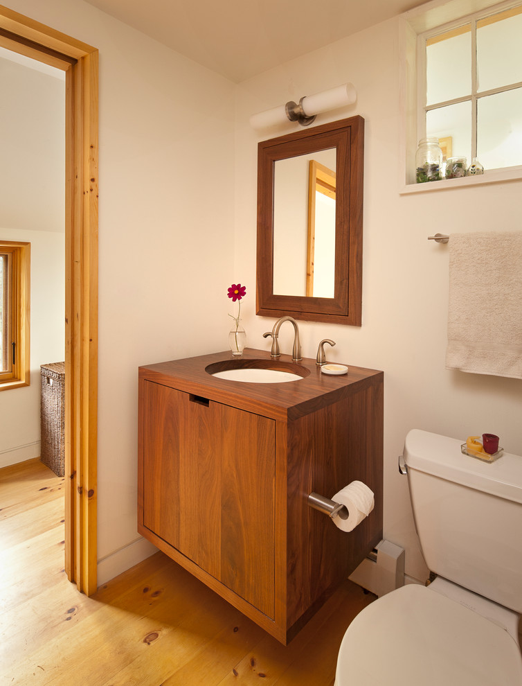 This is an example of a contemporary bathroom in Portland Maine with an undermount sink, flat-panel cabinets, medium wood cabinets, wood benchtops and a two-piece toilet.