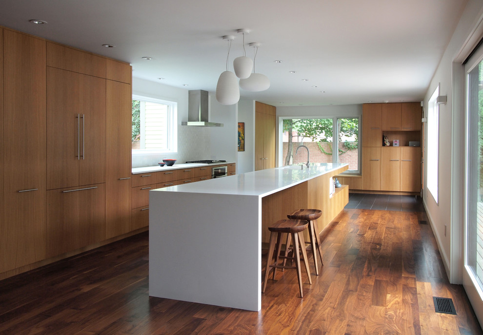Inspiration for a large modern galley kitchen in New York with an integrated sink, flat-panel cabinets, medium wood cabinets, solid surface benchtops, white splashback, ceramic splashback, panelled appliances, dark hardwood floors and with island.