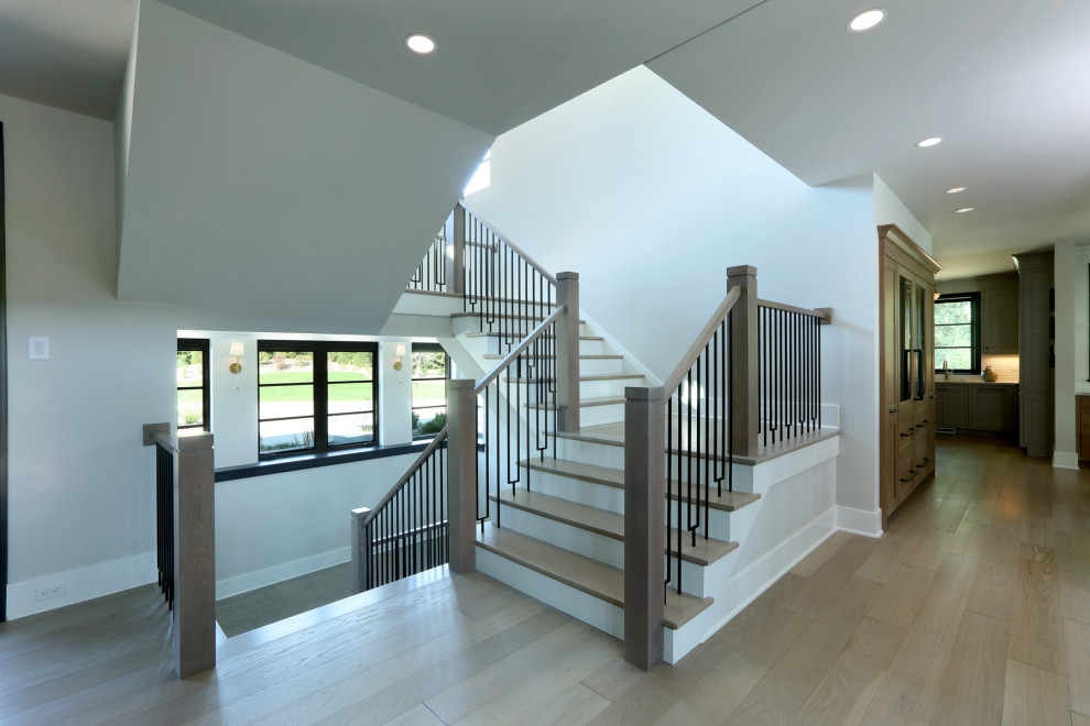 Photo of a large contemporary wood l-shaped staircase in Grand Rapids with wood risers and metal railing.