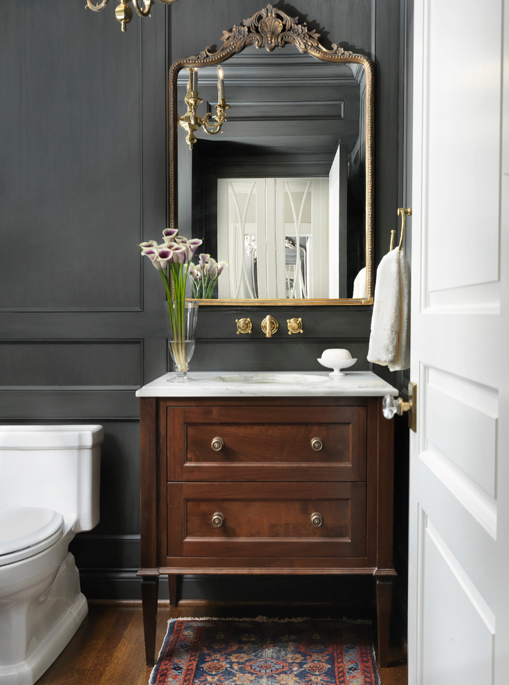 Inspiration for a small traditional powder room in St Louis with a one-piece toilet, black walls, medium hardwood floors, an undermount sink and marble benchtops.