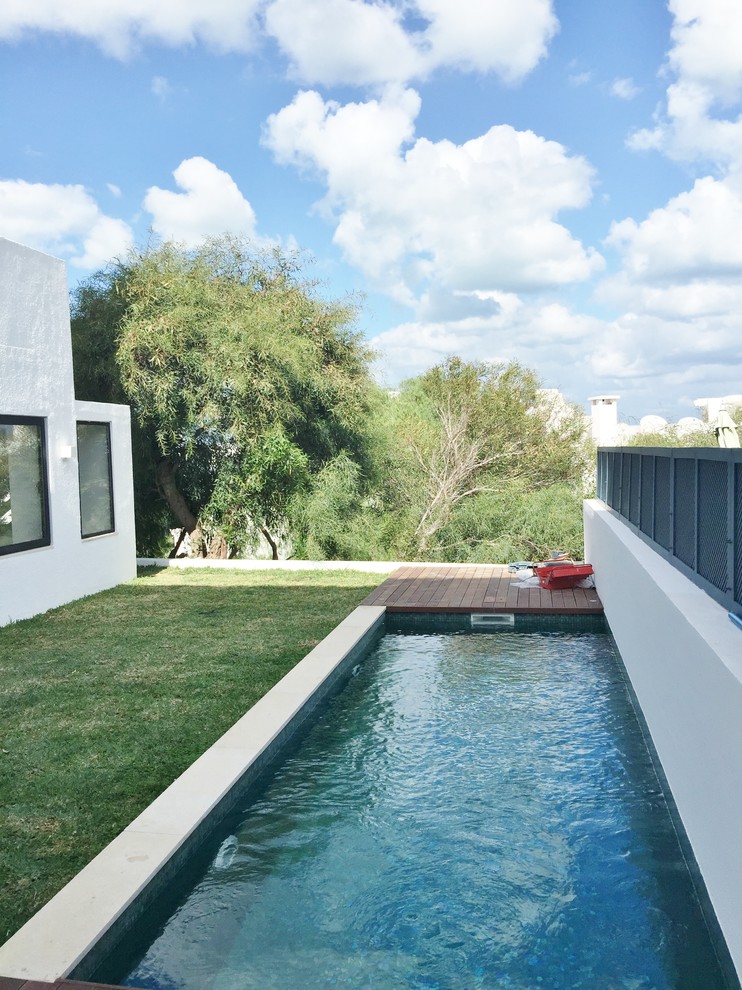 Aménagement d'un grand couloir de nage arrière contemporain rectangle avec une terrasse en bois.