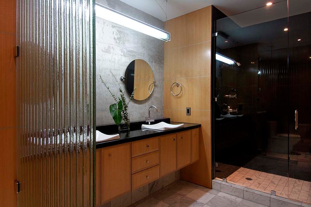 Photo of a mid-sized contemporary 3/4 bathroom in Hawaii with flat-panel cabinets, brown cabinets, an alcove shower, gray tile, cement tile, grey walls, ceramic floors, a vessel sink, solid surface benchtops, grey floor, a hinged shower door and black benchtops.