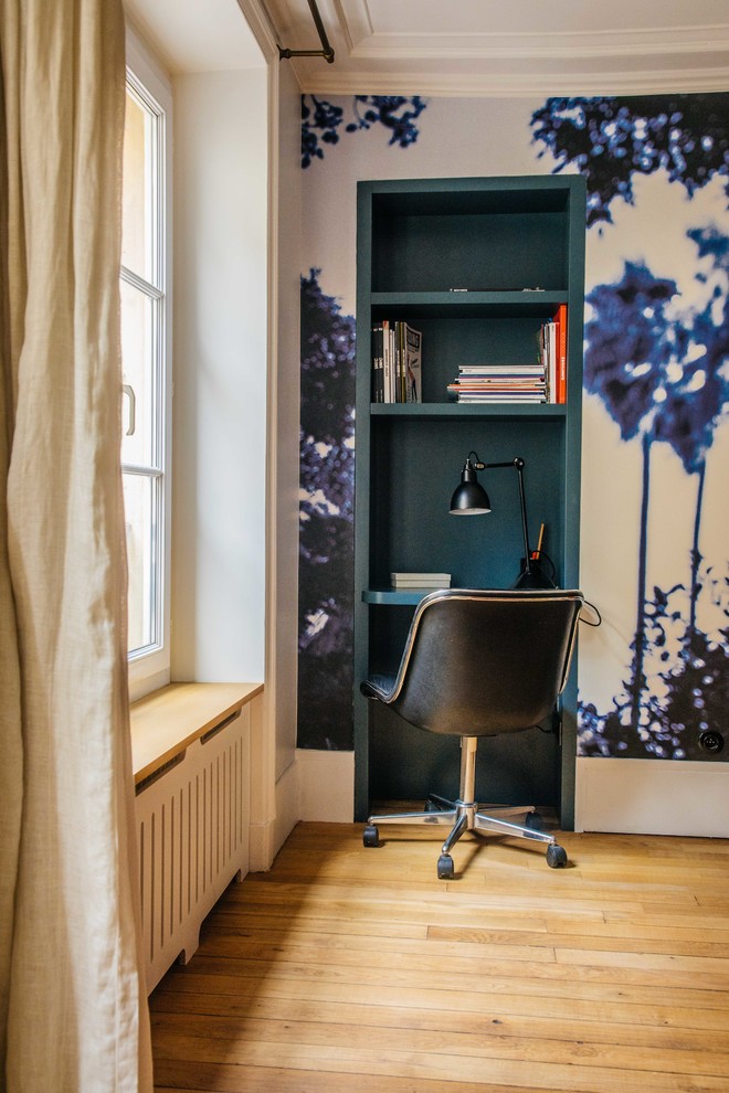 Mid-sized contemporary study room in Paris with blue walls, light hardwood floors and a built-in desk.