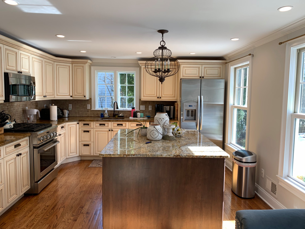 This is an example of a mid-sized transitional l-shaped eat-in kitchen in New York with an undermount sink, shaker cabinets, grey cabinets, quartz benchtops, grey splashback, limestone splashback, stainless steel appliances, medium hardwood floors, with island, brown floor and white benchtop.