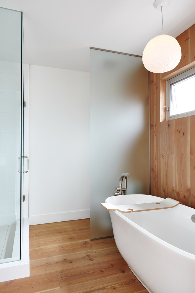 Inspiration for a mid-sized modern master bathroom in Toronto with flat-panel cabinets, medium wood cabinets, a freestanding tub, a corner shower, a one-piece toilet, white tile, porcelain tile, multi-coloured walls, light hardwood floors, a vessel sink, engineered quartz benchtops and a hinged shower door.