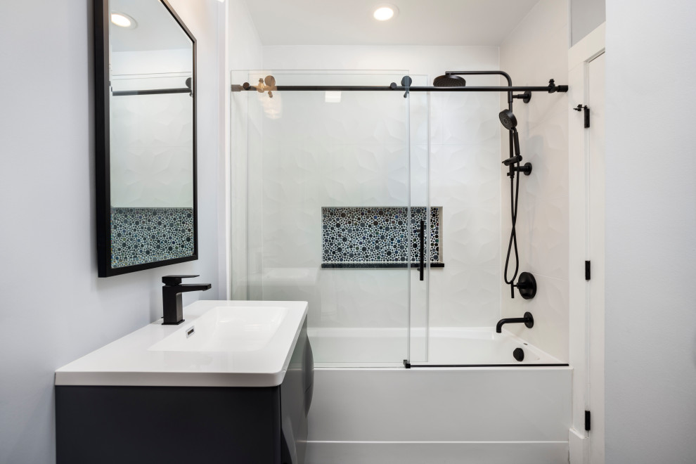 Exempel på ett mellanstort modernt vit vitt badrum, med grå skåp, ett platsbyggt badkar, en dusch/badkar-kombination, en toalettstol med hel cisternkåpa, svart kakel, keramikplattor, grå väggar, klinkergolv i porslin, ett nedsänkt handfat, bänkskiva i akrylsten och svart golv