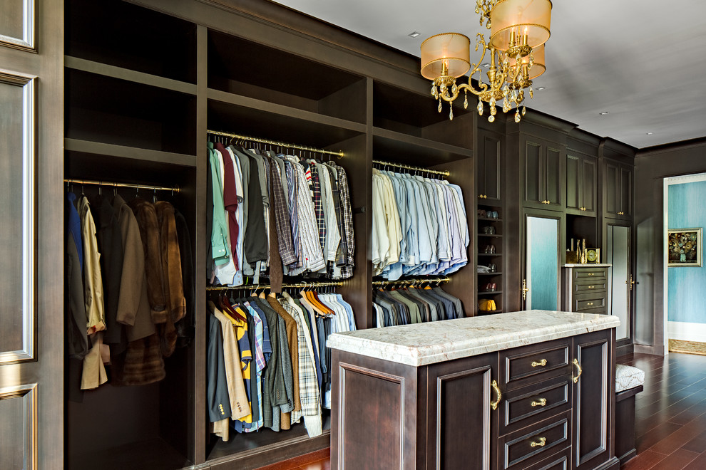 Photo of a large traditional men's walk-in wardrobe in New York with dark wood cabinets, medium hardwood floors and recessed-panel cabinets.