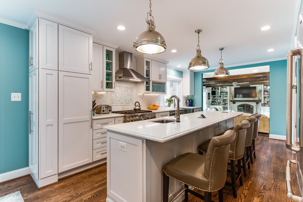 Eat-in kitchen - large transitional galley medium tone wood floor and brown floor eat-in kitchen idea in DC Metro with a farmhouse sink, shaker cabinets, white cabinets, quartz countertops, white backsplash, ceramic backsplash, stainless steel appliances, an island and white countertops