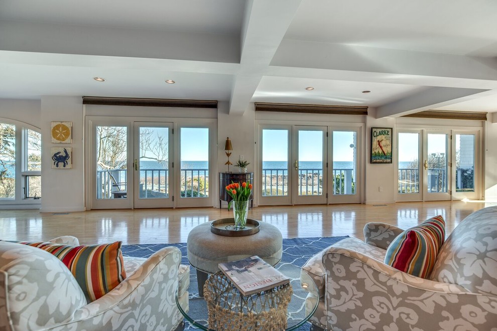 This is an example of a mid-sized beach style formal open concept living room in Boston with white walls, light hardwood floors, no fireplace, no tv and brown floor.