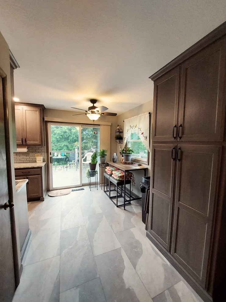 Mid-sized mountain style u-shaped ceramic tile and gray floor eat-in kitchen photo with a drop-in sink, dark wood cabinets, granite countertops, white backsplash, subway tile backsplash, stainless steel appliances and beige countertops