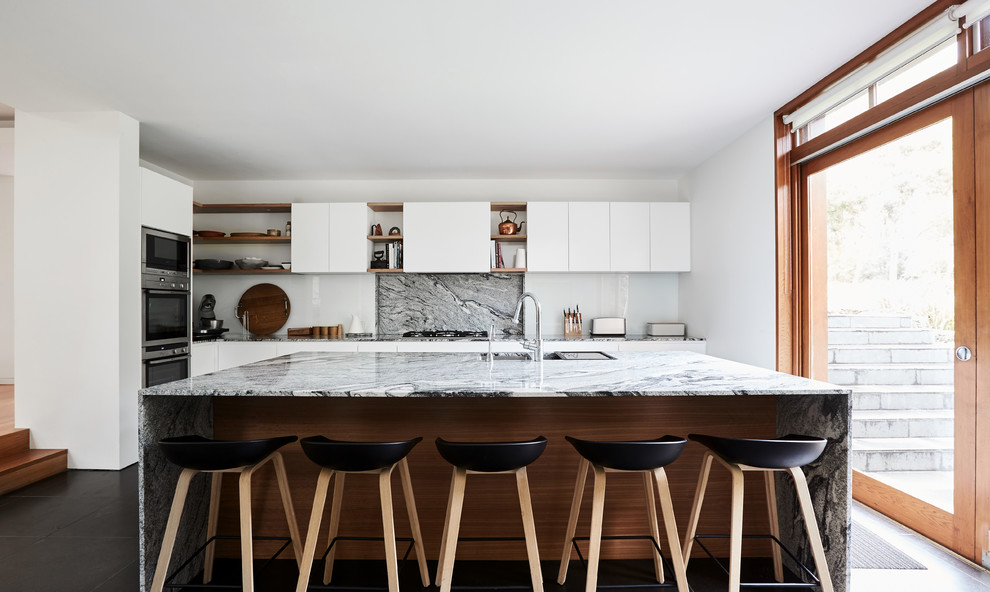 Design ideas for a large contemporary l-shaped kitchen in Melbourne with an undermount sink, white cabinets, granite benchtops, multi-coloured splashback, stone slab splashback, stainless steel appliances, with island, black floor, flat-panel cabinets and multi-coloured benchtop.