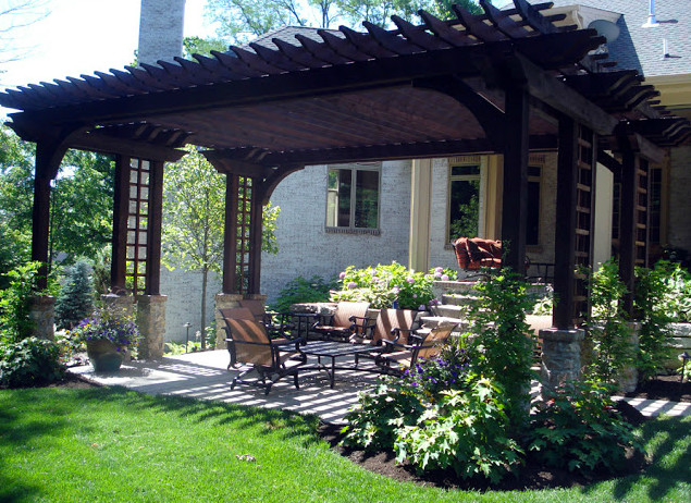 Large backyard verandah in Indianapolis with brick pavers and a pergola.