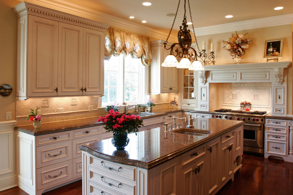 Mid-sized l-shaped dark wood floor enclosed kitchen photo with an undermount sink, raised-panel cabinets, white cabinets, granite countertops, beige backsplash, stainless steel appliances and an island