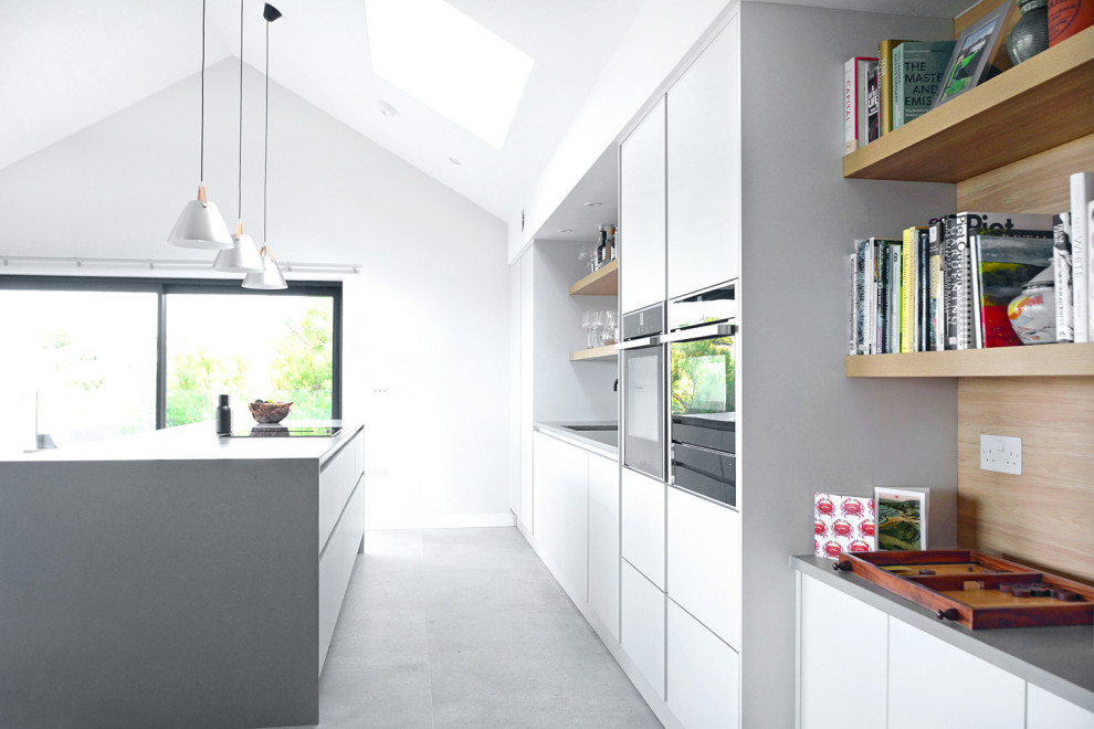 Idéer för ett stort minimalistiskt grå linjärt kök med öppen planlösning, med en integrerad diskho, släta luckor, vita skåp, bänkskiva i kvartsit, vitt stänkskydd, glaspanel som stänkskydd, integrerade vitvaror, klinkergolv i porslin och grått golv