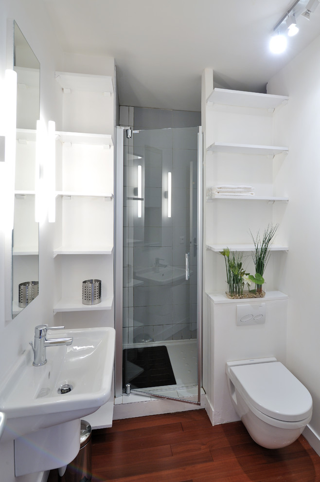 Design ideas for a small contemporary 3/4 bathroom in Paris with a wall-mount sink, an alcove shower, a wall-mount toilet, white walls, dark hardwood floors, open cabinets and white cabinets.