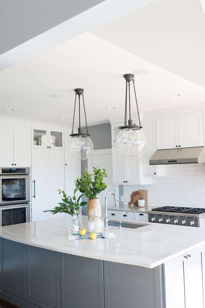 Eat-in kitchen - large transitional light wood floor and brown floor eat-in kitchen idea in Chicago with white cabinets, marble countertops, white backsplash, ceramic backsplash, an island and white countertops