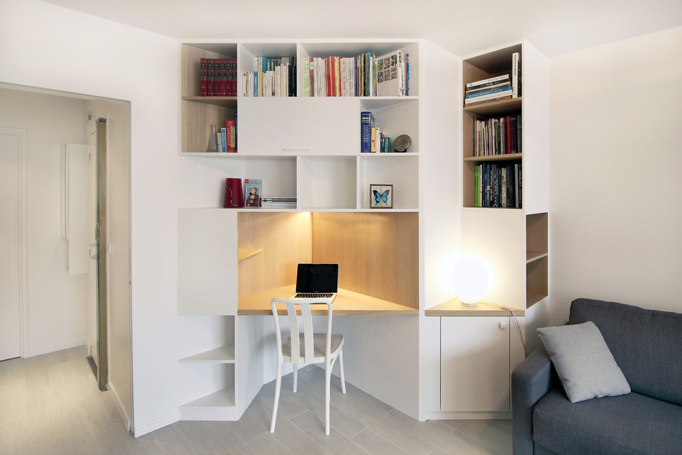 Mid-sized contemporary study room in Paris with a built-in desk, white walls, light hardwood floors and no fireplace.