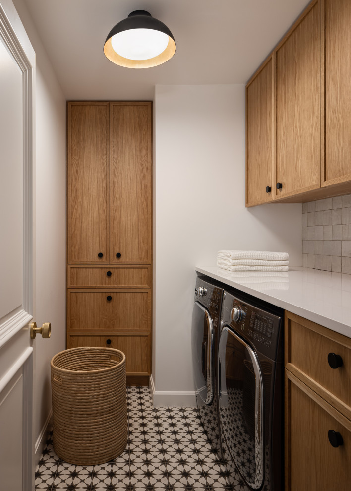 Transitional galley laundry room in Kansas City with recessed-panel cabinets, brown cabinets, a side-by-side washer and dryer and white benchtop.
