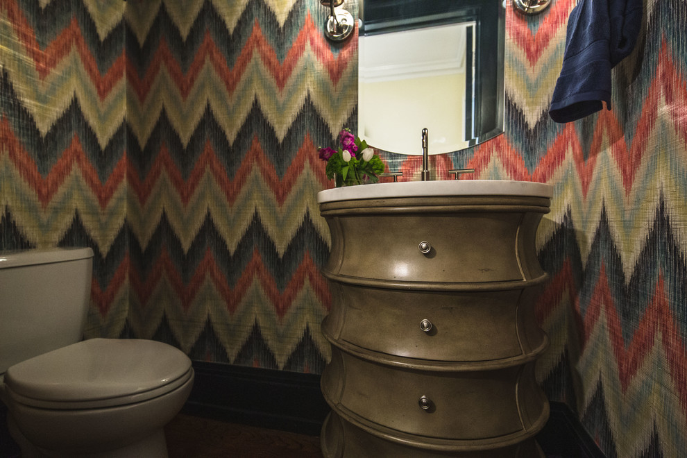 Photo of a mid-sized transitional powder room in Cleveland with furniture-like cabinets, a two-piece toilet, multi-coloured walls, dark hardwood floors, an undermount sink, marble benchtops, brown floor and white benchtops.