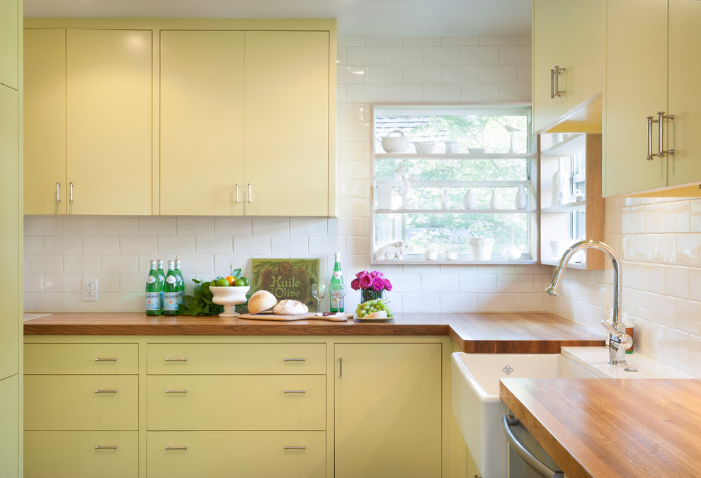 Contemporary separate kitchen in Austin with a farmhouse sink, wood benchtops, flat-panel cabinets, yellow cabinets, white splashback and subway tile splashback.