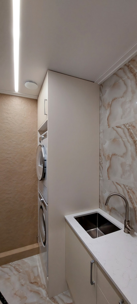 Inspiration for a medium sized contemporary single-wall separated utility room in Moscow with a submerged sink, flat-panel cabinets, white cabinets, composite countertops, beige splashback, porcelain splashback, beige walls, porcelain flooring, a stacked washer and dryer, beige floors and beige worktops.